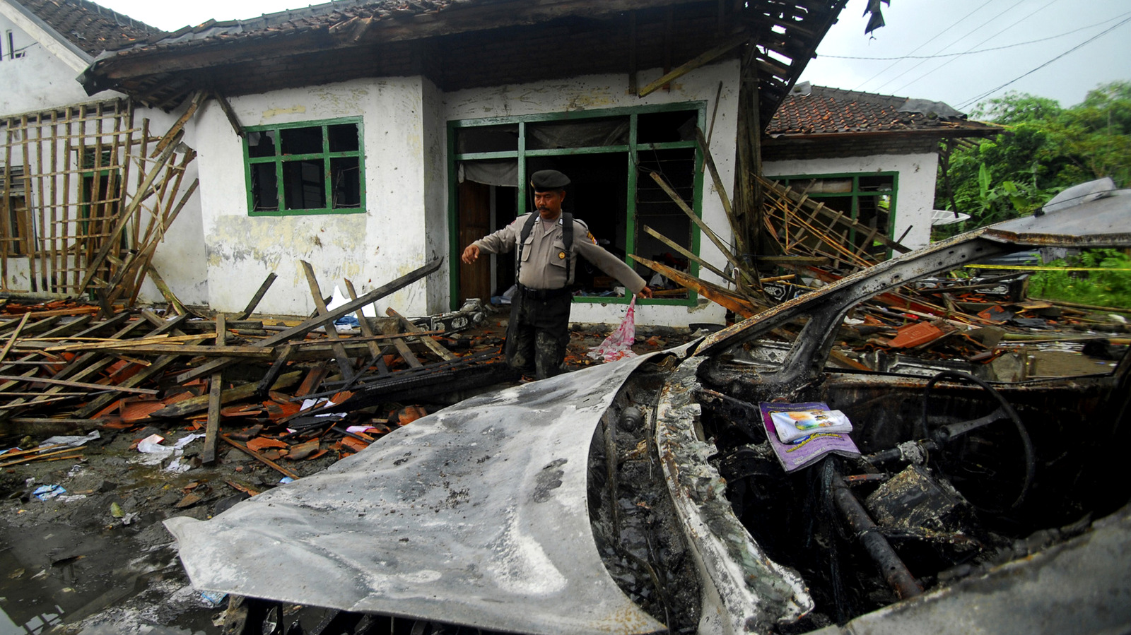 A police officer inspects the damage at the house of a member of Ahmadiyah sect after it was attacked by a Sunni mob in Pandeglang, Banten province, Indonesia, Monday, Feb. 7, 2011. The machete-wielding mob on Sunday attacked the home of the minority sect leader in central Indonesia, killing three and wounding six others, police and witnesses said. (AP Photo)