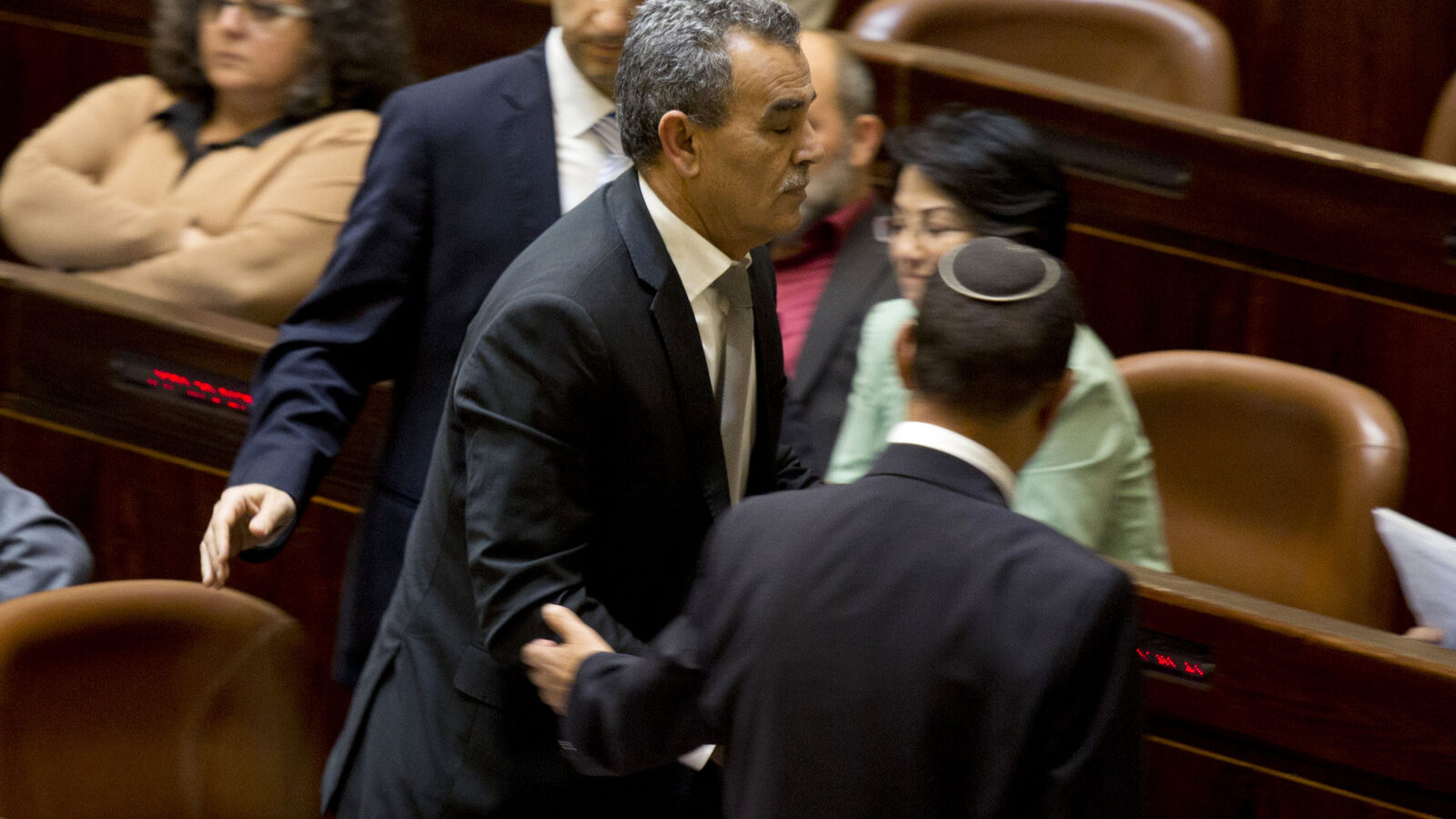 Jamal Zahalka an Israeli-Arab lawmaker from the Joint Arab List, is taken from the plenum in the Knesset, Israel's parliament in Jerusalem, Monday, Feb. 8, 2016. Israel’s government is promoting legislation to ban three Arab lawmakers who met with families of Palestinians who carried out deadly attacks. The Arab parliamentarians, Hanin Zoabi, Basel Ghattas and Jamal Zahalka, met the families last week to help lobby the release of some of their relatives’ bodies. (AP Photo/Ariel Schalit)