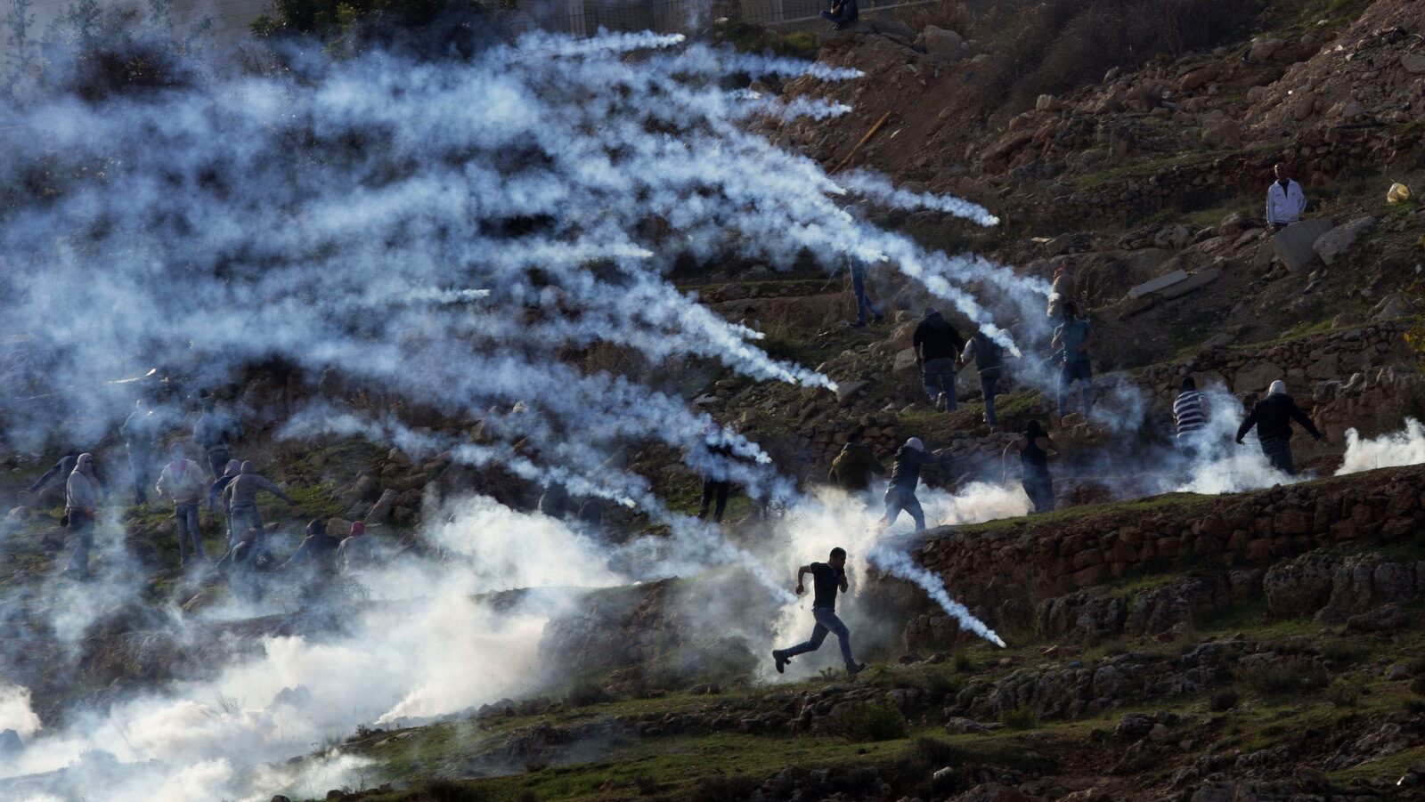 Palestinian protesters run from tear gas fired by Israeli troops during a protest of outside Ofer security prison in the occupied West Bank city of Ramallah. (AP Photo/Majdi Mohammed)