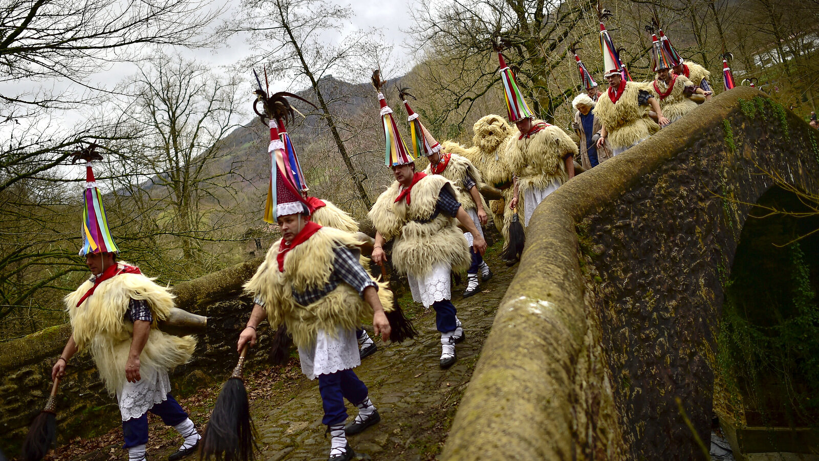 Joaldunaks walk on their way to take part in the Carnival between the Pyrenees villages of Ituren and Zubieta, northern Spain, Monday, Feb.1, 2016. In one of the most ancient carnivals in Europe, dating from before the Roman empire, companies of Joaldunak (cowbells) made up of residents of two towns, Ituren and Zubieta, parade the streets costumed in sandals, lace petticoats, sheepskins around the waist and shoulders, coloured neckerchiefs, conical caps with ribbons and a hyssop of horsehair in their right hands and cowbells hung across their lower back. (AP Photo/Alvaro Barrientos)