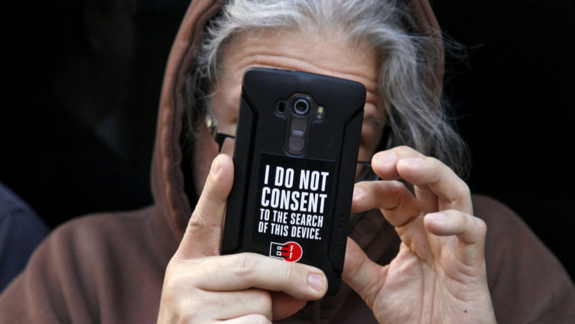 A man holds up his phone during a rally in support of data privacy outside the Apple store Tuesday, Feb. 23, 2016, in San Francisco. Protesters assembled in more than 30 cities to lash out at the FBI for obtaining a court order that requires Apple to make it easier to unlock an encrypted iPhone used by a gunman in December's mass murders in California. (AP Photo/Eric Risberg)