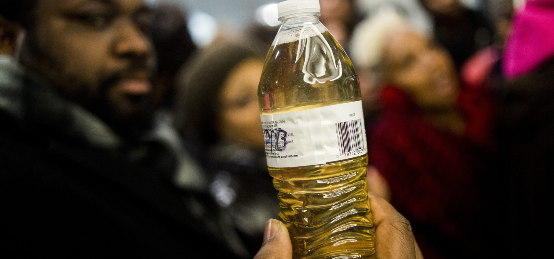 Pastor David Bullock holds up a bottle of Flint water as Michigan State Police hold a barrier to keep protestors out of the Romney Building, where Gov. Rick Snyder's office resides on Thursday, Jan. 14, 2016, in Lansing, Mich. (Jake May/The Flint Journal-MLive.com via AP)