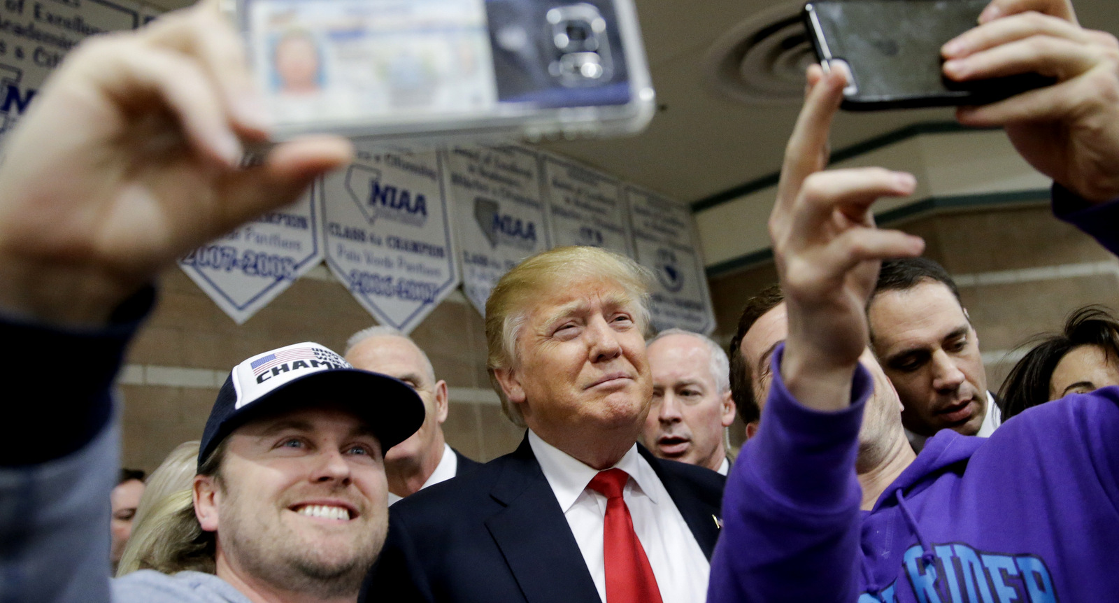 Republican presidential candidate Donald Trump, middle, takes a picture with supporters at a caucus site, Tuesday, Feb. 23, 2016, in Las Vegas. (AP Photo/Jae C. Hong)
