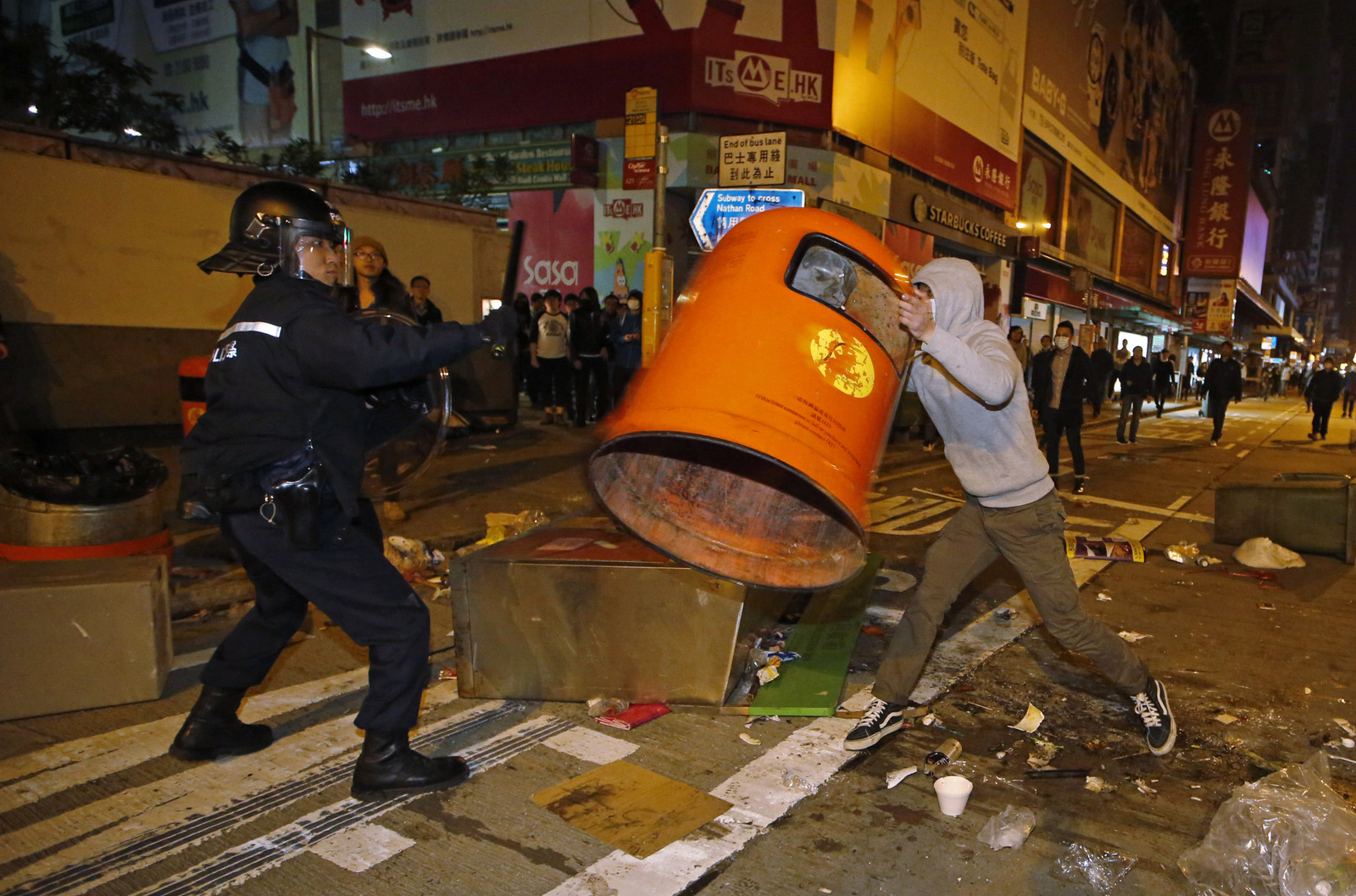 A rioter tries to throw a litter bin at police on a street in Mong Kok district of Hong Kong, Tuesday, Feb. 9, 2016. Hong Kong's Lunar New Year celebration descended into chaotic scenes as protesters and police, who fired warning shots into the air, clashed over a street market selling fish balls and other local holiday delicacies, leaving dozens injured and arrested. (AP Photo/Kin Cheung)