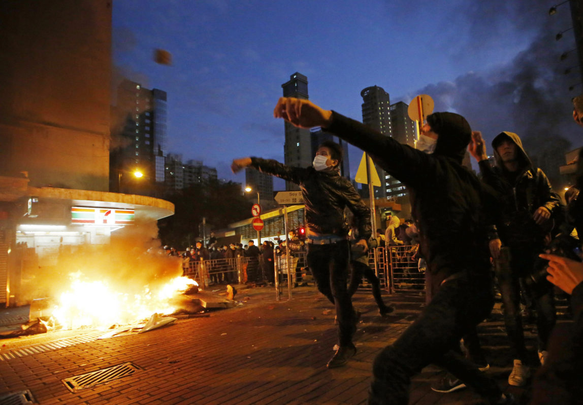 Protestors throw bricks at police and light fires on streets in Mongkok district of Hong Kong, Tuesday, Feb. 9, 2016. Protesters engaged in running battles with police, pelting officers with bricks and bottles and setting fires on the street Monday night and early Tuesday. (AP Photo/Kin Cheung)