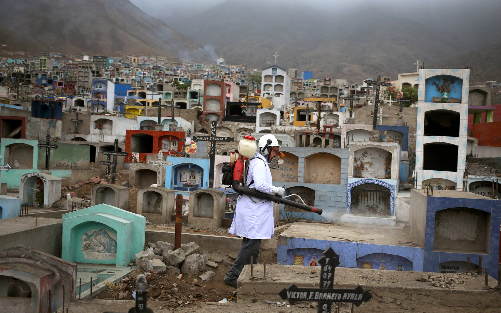A health worker fumigates to prevent Dengue, Chikungunya and Zika virus, at the Martires 19 de Julio cemetery in the outskirts of Lima, Peru, Tuesday, Feb 9, 2016. (AP Photo/Martin Mejia)