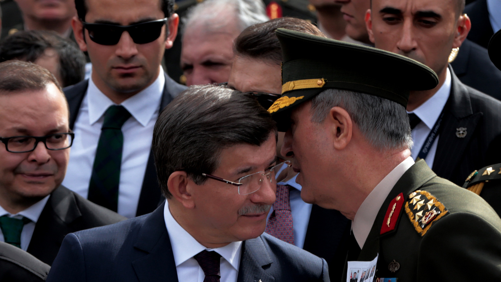 Turkey's Chief of Staff Gen. Hulusi Akar, right, whispers into the ear of Prime Minister Ahmet Davutoglu. (AP Photo/Burhan Ozbilici)