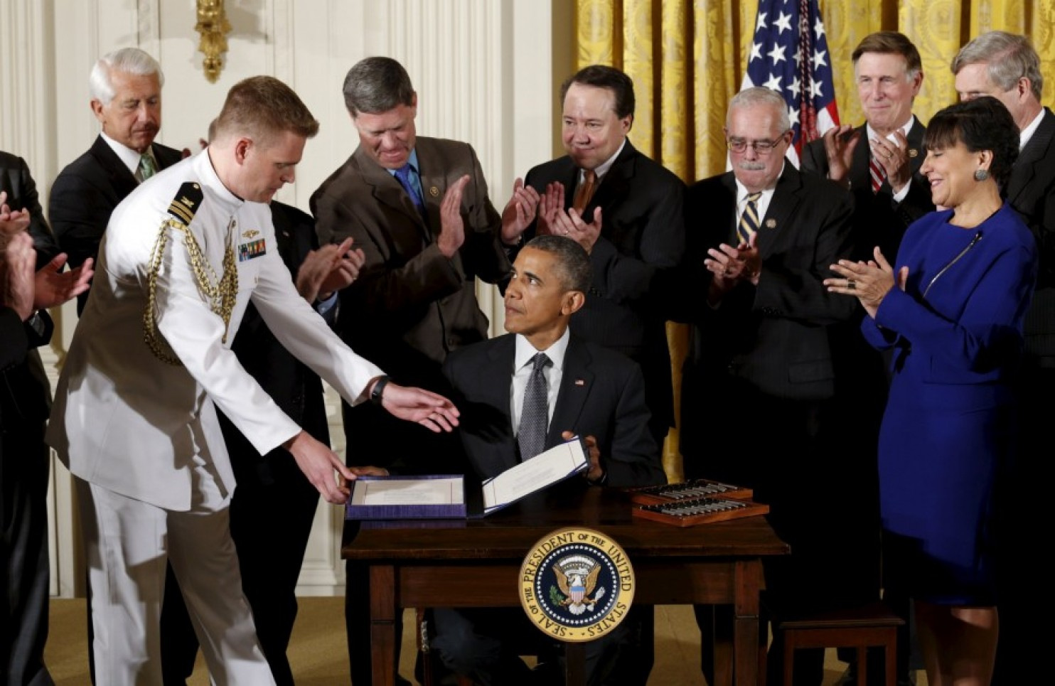 Surrounded by Cabinet officials and members of Congress, President Barack Obama signs H.R. 2146, which sandwiched in other measures, provided a 'fast track; to implementing the TPP. (AP Photo/Carolyn Kaster)