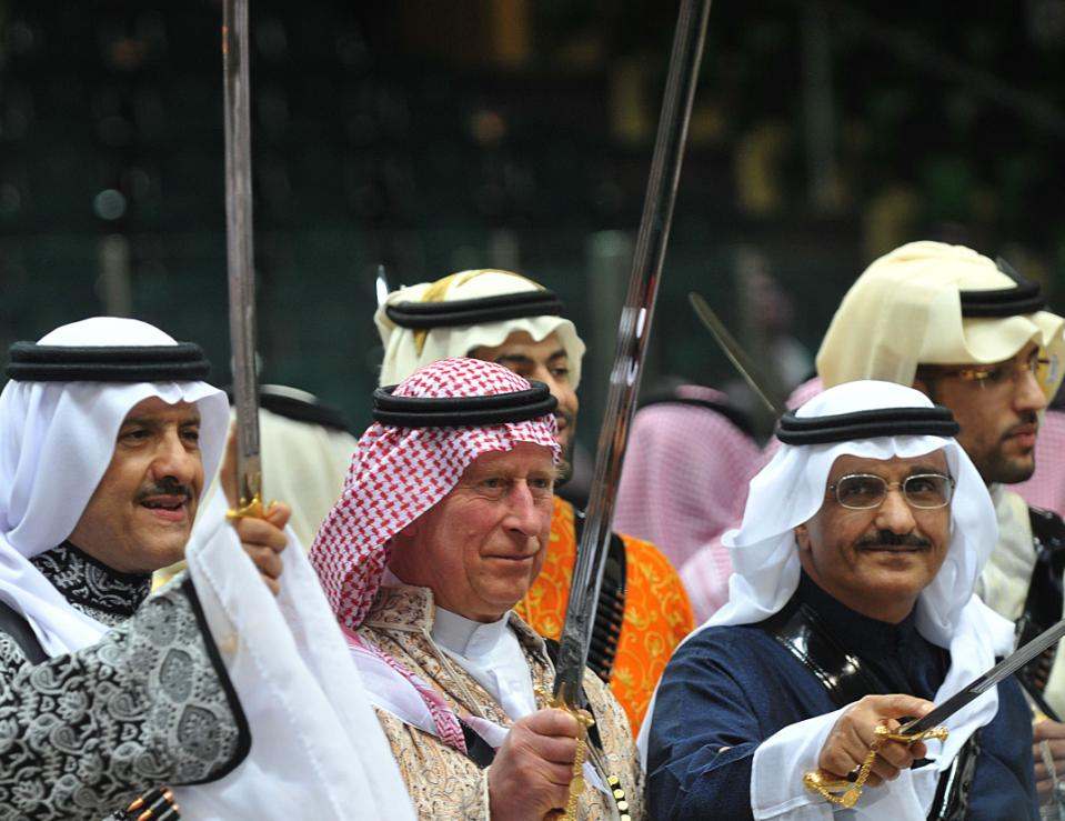Britain's Prince Charles, center, wears traditional Saudi uniform as he dances with a sword during Janadriya culture festival at Der'iya in Riyadh, Tuesday, Feb. 18, 2014. Prince Charles arrived in Kingdom of Saudi Arabia just as Britain was closing a deal for sale of Typhoon Jets to Saudi Arabia. (AP Photo/Fayez Nureldine, pool)