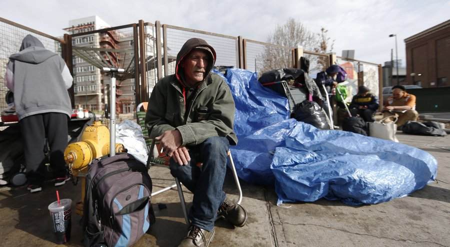 In this Monday, March 7, 2016, photograph, Salvatore Garofalo sits in a lawn chair in a makeshift homeless camp across from the Denver Rescue Mission in downtown Denver. City officials are planning to evict people on Tuesday from the homeless camps that have popped up around homeless shelters and in public places around the Mile High City. (AP Photo/David Zalubowski)