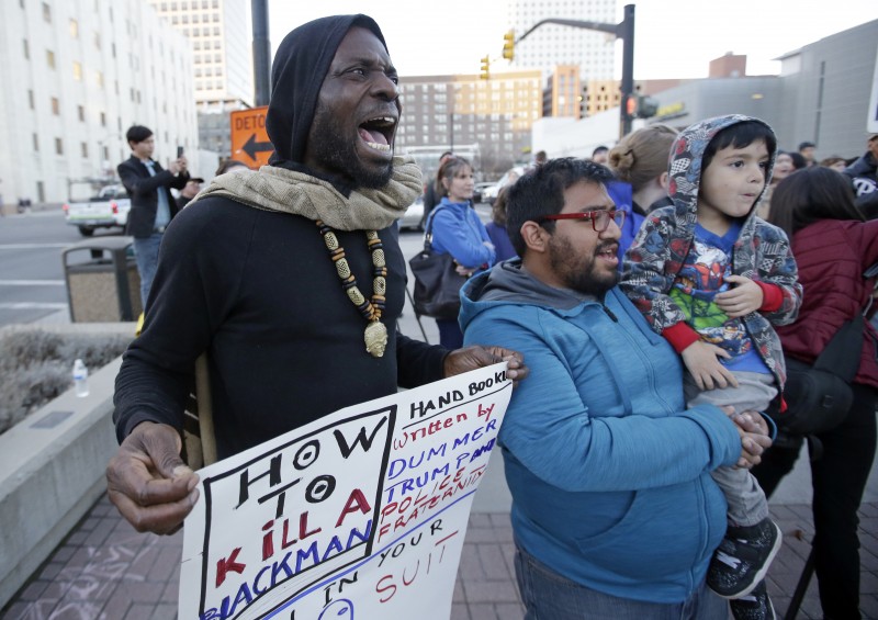Protester Nacom Koffi, left, shouts during rally for a 17-year-old boy who is in critical condition after being shot Saturday by Salt Lake City police Monday, Feb. 29, 2016, in Salt Lake City. The shooting that occurred near the city's primary homeless shelter on a street notorious for drug deals and fights raised questions about police use of force and the role of race. (AP Photo/Rick Bowmer)