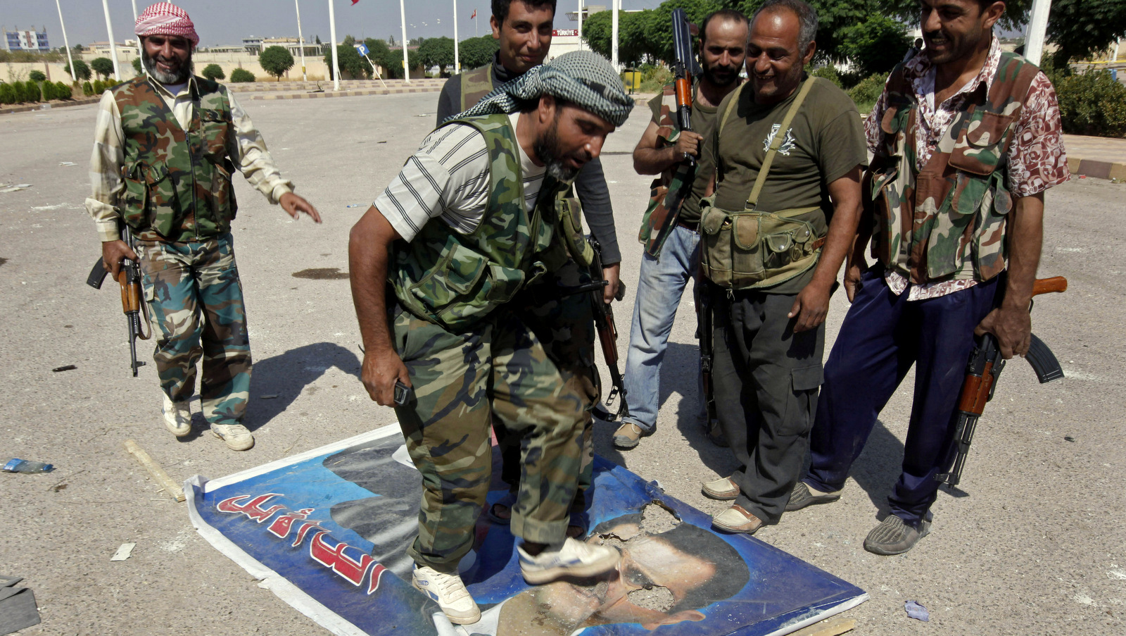 A Free Syrian Army fighter from the Al-Faruk brigade, center, steps on a portrait of Syrian President Bashar Assad, Sept. 22, 2012 (AP/Hussein Malla)