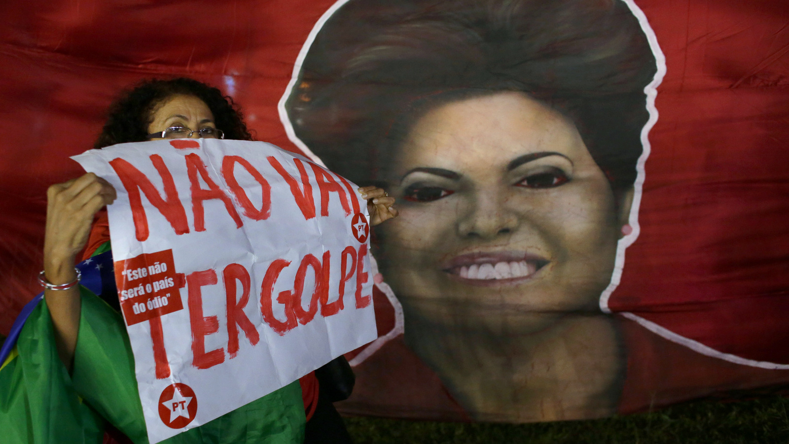 Woman shows poster written in Portuguese "There will not be a coup" next to a picture of Brazil's President Dilma Rousseff, during a rally in her support and of former President Luiz Inacio Lula da Silva, in Brasilia, Brazil, Friday, March 18, 2016. Supporters of Silva and Rousseff gathered for rallies in a handful of cities across Brazil, particularly in the industrial south, where the former factory worker has his base. Silva has tageted in an alleged corruption investigation involving the Brazil oil giant Petrobras. (AP Photo/Eraldo Peres)