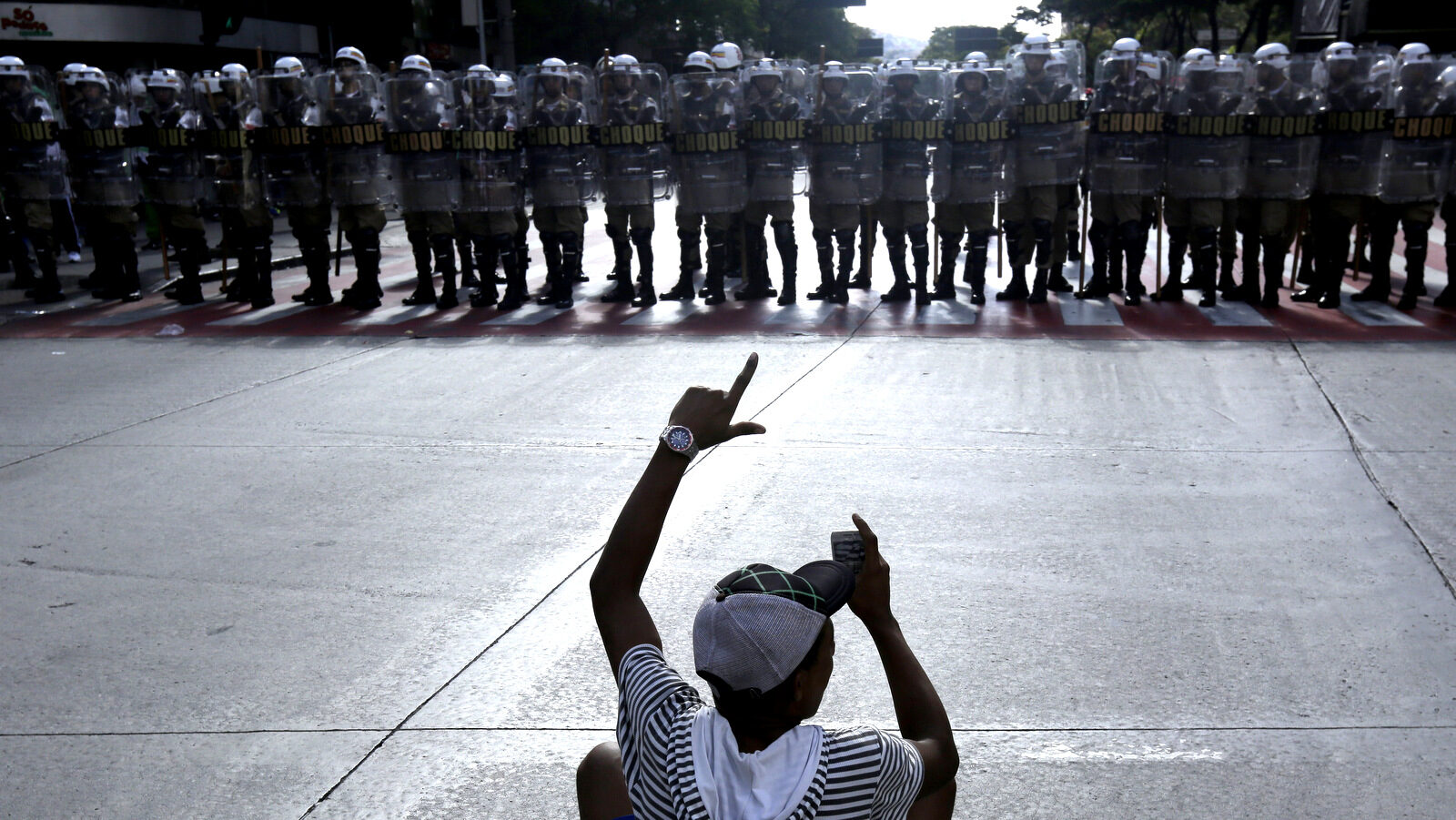 A demonstrator films a line of police during a protest against the World Cup in Rio de Janeiro, Brazil. (AP Photo/Bruno Magalhaes, File)