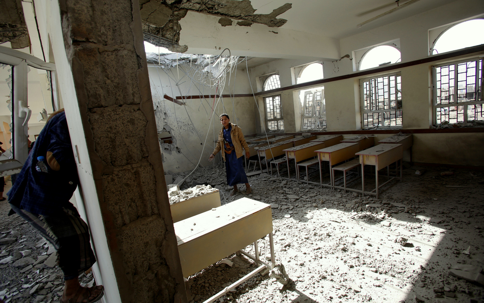 Boys walk around in a classroom at a school damaged by Saudi-led airstrikes in Sanaa, Yemen, Monday, July 20, 2015. The death toll in Yemen from the Shiite rebel shelling of a town near the southern port city of Aden rose on Monday to nearly 100, the head of an international aid group said, describing it as "the worst day" for the city and its surroundings in over three months of fighting. (AP Photo/Hani Mohammed)