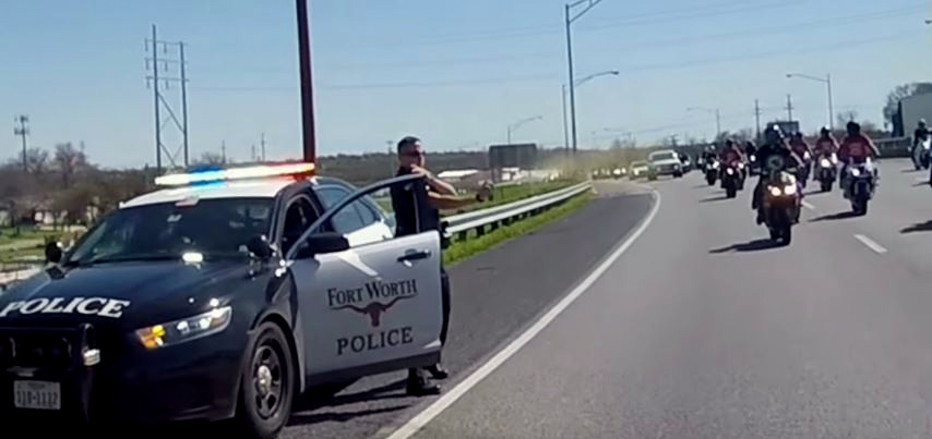 Screenshot from a Facebook video depicting a Fort Worth officer spraying pepper spray into a group of oncoming motorcyclists.