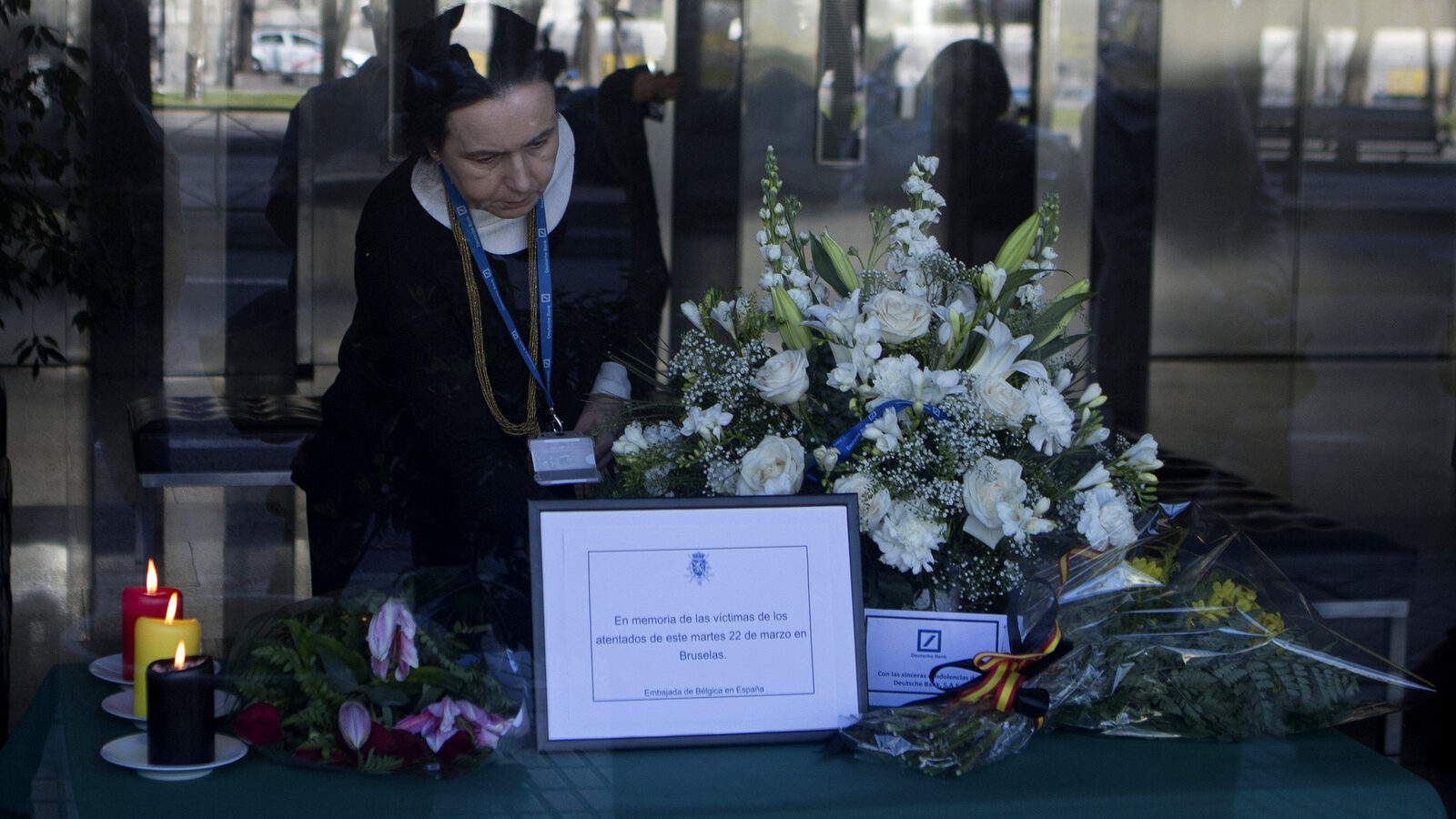 A woman places a card for display inside the Belgian embassy in Madrid, Spain, Wednesday, March 23, 2016, a day after Tuesday's deadly suicide attacks on the Brussels airport and its subway system. Spain's Interior Ministry said that for the moment Spain was maintaining its Security Alert Level 4, one step below the maximum. (AP Photo/Paul White)