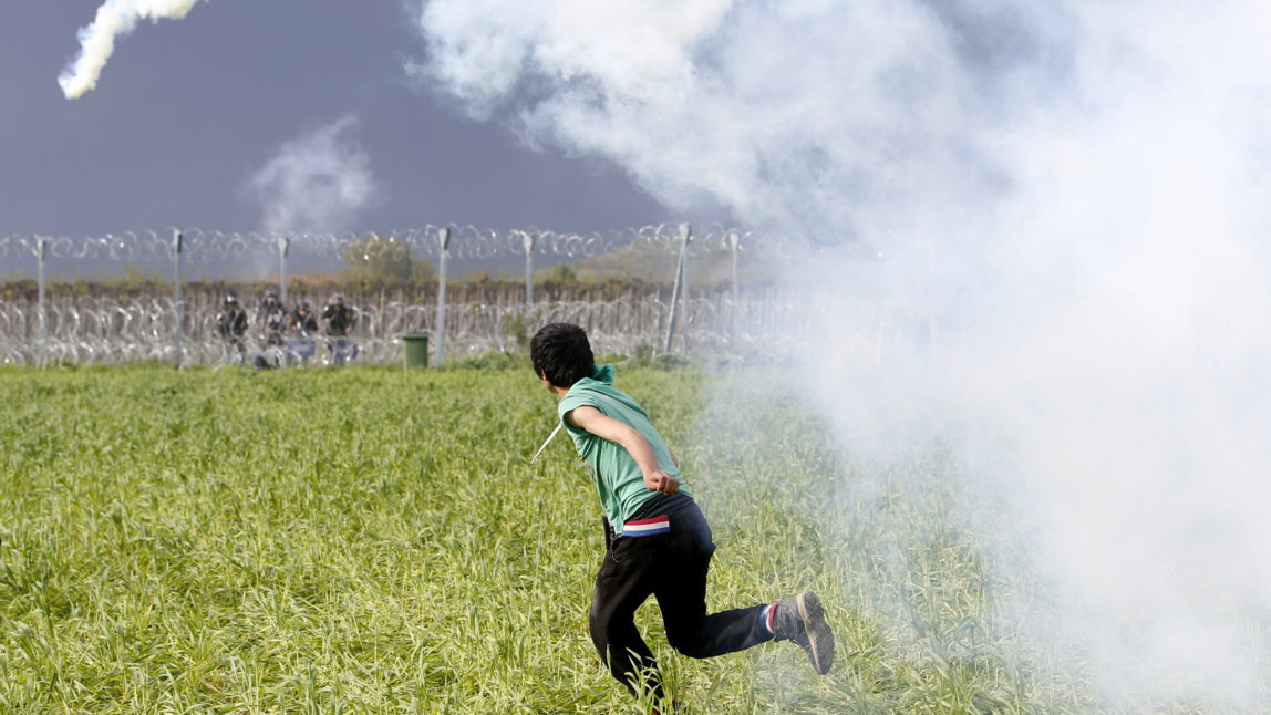 A migrant man throws a can of the tear gas back toward Macedonian police during a protest at the northern Greek border point of Idomeni, Greece, Sunday, April 10, 2016. Thousands of migrants protested at the border and clashed with Macedonian police. (AP Photo/Amel Emric)