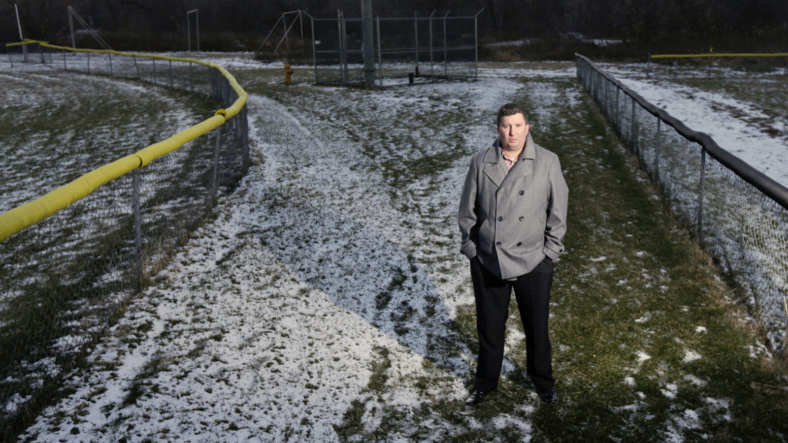 In this Jan. 21, 2016, file photo, Michael Hickey poses near Hoosick Falls municipal well 7 between two baseball fields in Hoosick Falls, N.Y. PFOA, long used in the manufacuring of Teflon pans, Gore-Tex jackets, ski wax, and many other products has turned up in the water in factory towns around the country like Hoosick Falls. Hickey, a local insurance underwriter, exposed the contamination in Hoosick Falls, a bucolic community near the Vermont state line. (AP/Mike Groll)