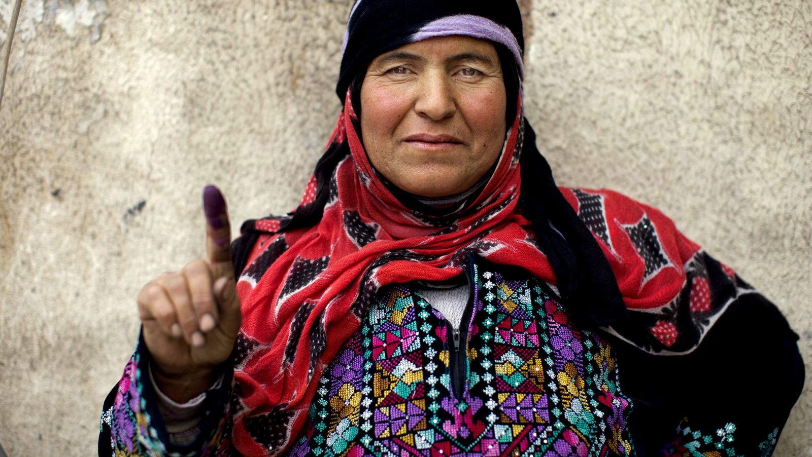 A Syrian woman poses for a photograph showing her inked finger after voting outside a polling station during the Syrian parliamentary election in Damascus, Syria, Wednesday, April 13, 2016. (AP Photo/Hassan Ammar)