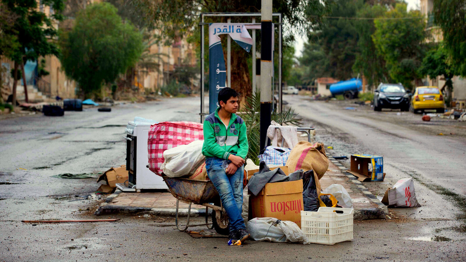 In this picture taken Thursday, April 14, 2016, a Syrian boy waits his family to loads their belongings onto a bus in the town of Palmyra in the central Homs province, Syria. Thousands of residents of this ancient town who fled Islamic State rule are returning briefly to check on their homes and salvage what they can _ some carpets, blankets, a fridge or a few family mementos. (AP Photo/Hassan Ammar)