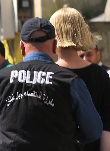 A Lebanese policeman escorts Australian TV presenter Tara Brown, who is seen handcuffed, as she is taken from a Lebanese courthouse where she was questioned by an investigative judge over suspicion of taking part in an abduction attempt of two Lebanese-Australian children, in Baabda, east of Beirut, Lebanon, Monday April, 18, 2016. (AP Photo/Hussein Malla)