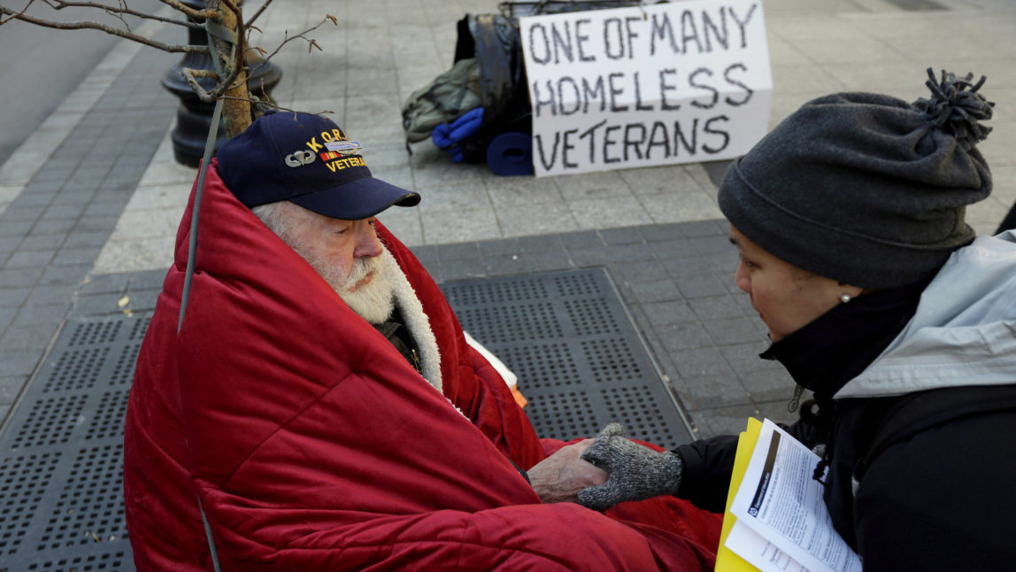 Homeless Korean War veteran Thomas Moore, 79, left, speaks with Boston Health Care for the Homeless street team outreach coordinator Romeena Lee on a sidewalk in Boston. M (AP/Steven Senne)