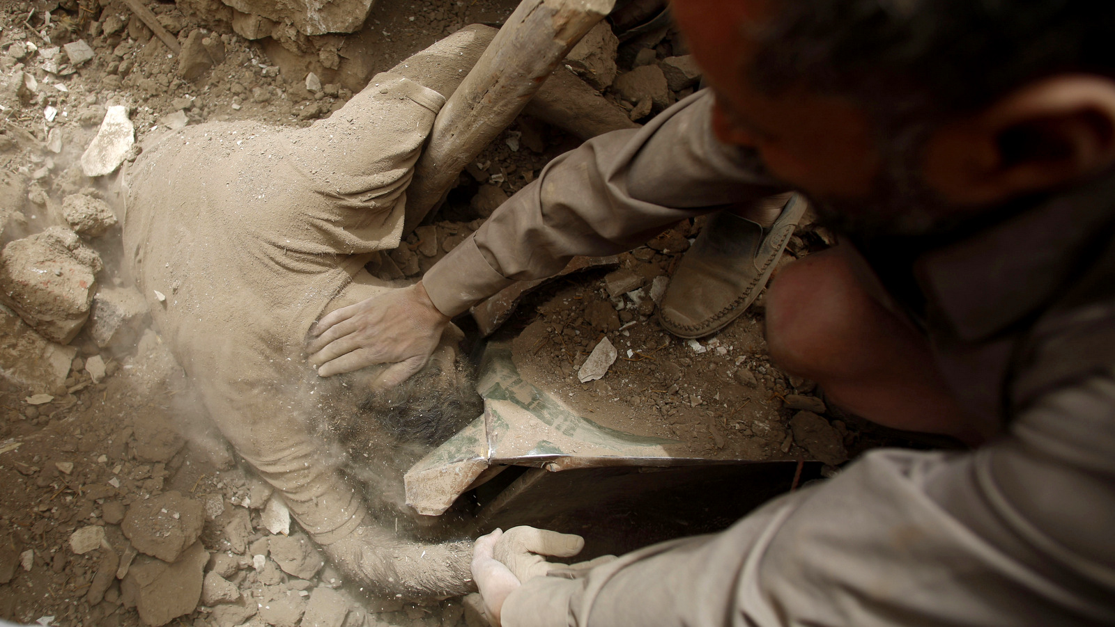 People uncover the body of a man from under the rubble of houses destroyed by U.S.-backed coalition airstrikes in the old city of Sanaa, Yemen. (AP/Hani Mohammed)