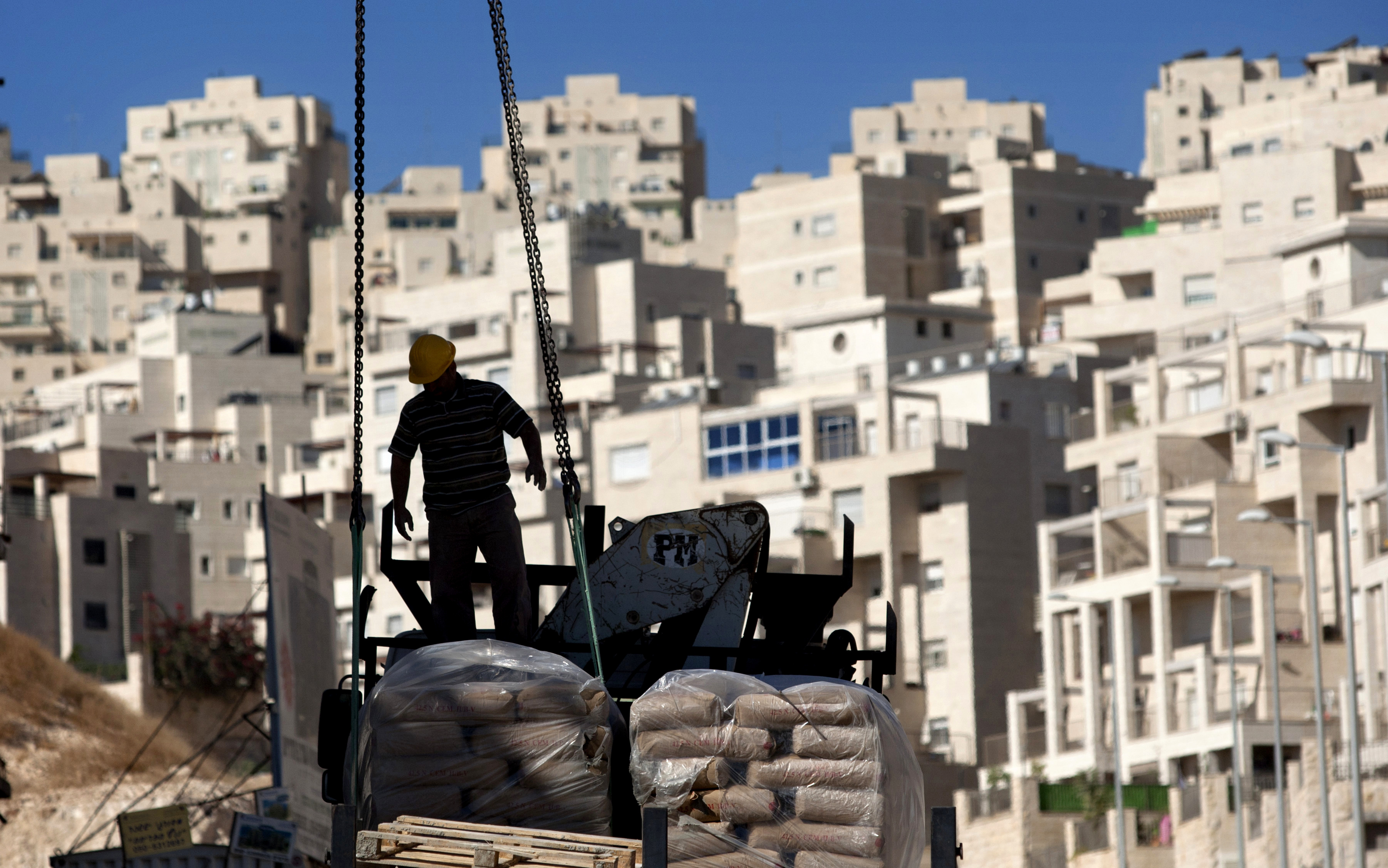 A worker stands by construction materials to unload at a Israeli Settlment unit in an east Jerusalem neighborhood. (AP Photo/Sebastian Scheiner)