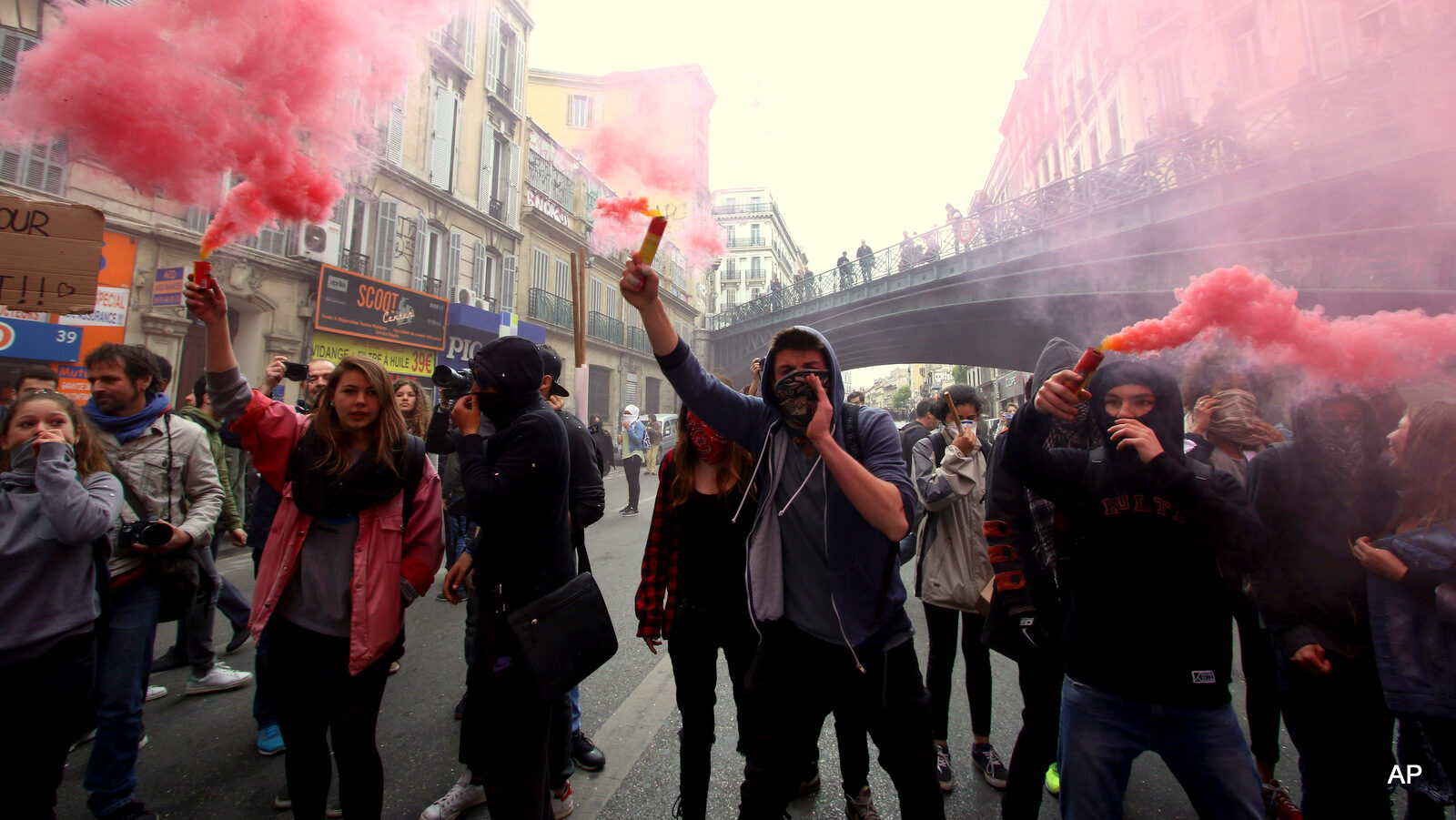 Students burn flares and shout slogans during a demonstration in Marseille, southern France, Thursday, April 28, 2016, during a nationwide day of protest. Student organizations and employee unions have joined to call for protests across France to reject a government reform relaxing the 35-hour working week and other labour rules.(AP Photo/Claude Paris)