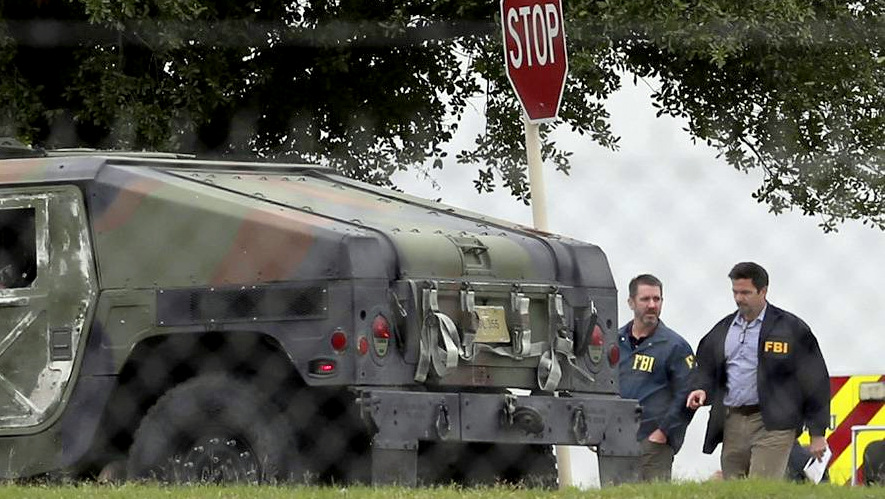 FBI officials walk behind an military vehicle near the scene of a shooting at Joint Base San Antonio-Lackland, Friday, April 8, 2016, in San Antonio. (John Davenport/The San Antonio Express-News via AP)