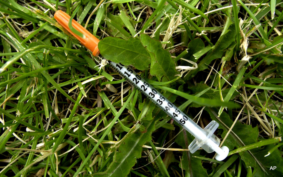 A syringe lies in the grass on a playing field near Charlestown High School, in the Charlestown neighborhood of Boston.