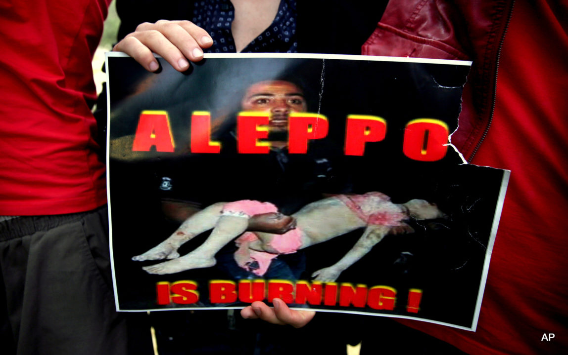 A Syrian man holds a sign during a protest in front of the United Nations headquarters in Beirut, Lebanon, Sunday, May 1, 2016, against Syrian President Bashar Assad's military operations in areas held by insurgents around the country, mostly in the northern city of Aleppo.