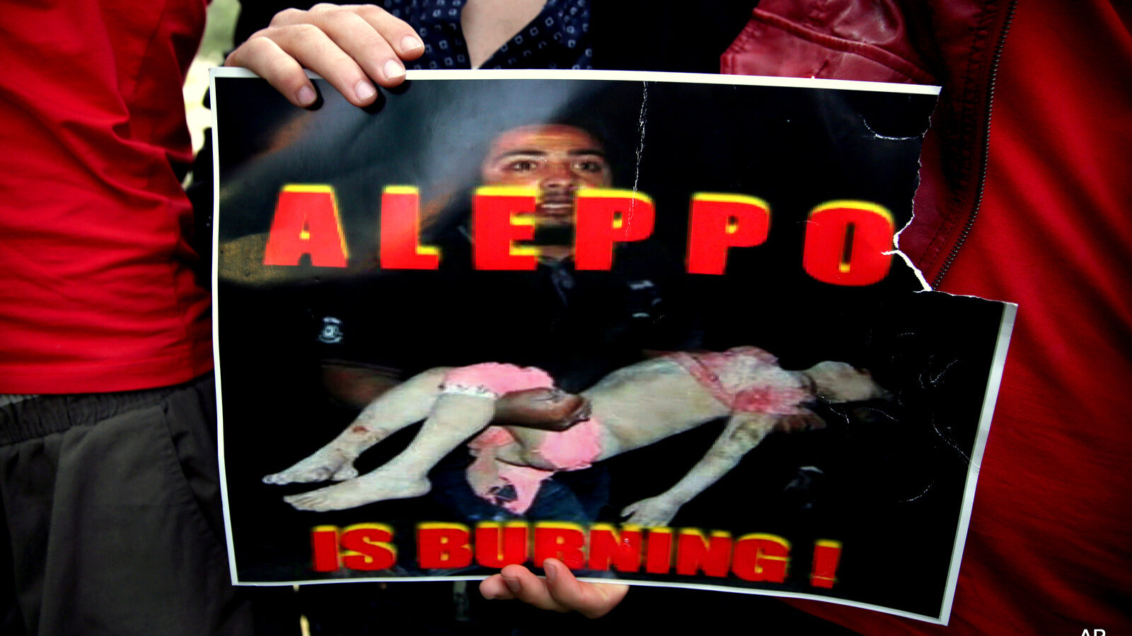 A Syrian man holds a sign during a protest in front of the United Nations headquarters in Beirut, Lebanon, Sunday, May 1, 2016, against Syrian President Bashar Assad's military operations in areas held by insurgents around the country, mostly in the northern city of Aleppo.