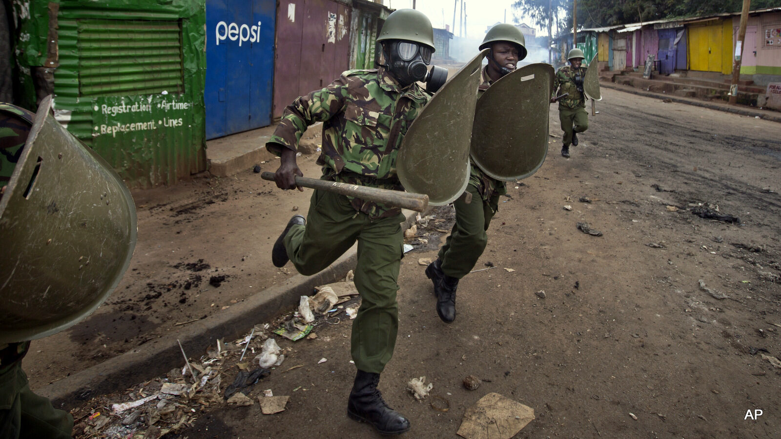 Kenyan police charge as they engage in running battles between police firing tear gas and protesters throwing rocks, in the Kibera slum of Nairobi, Kenya Monday, May 23, 2016. Kenya's police shot, beat and tear gassed opposition demonstrators across the country who tried to gather to call for the electoral commission to be dissolved due to allegations of bias and corruption. (AP Photo/Ben Curtis)