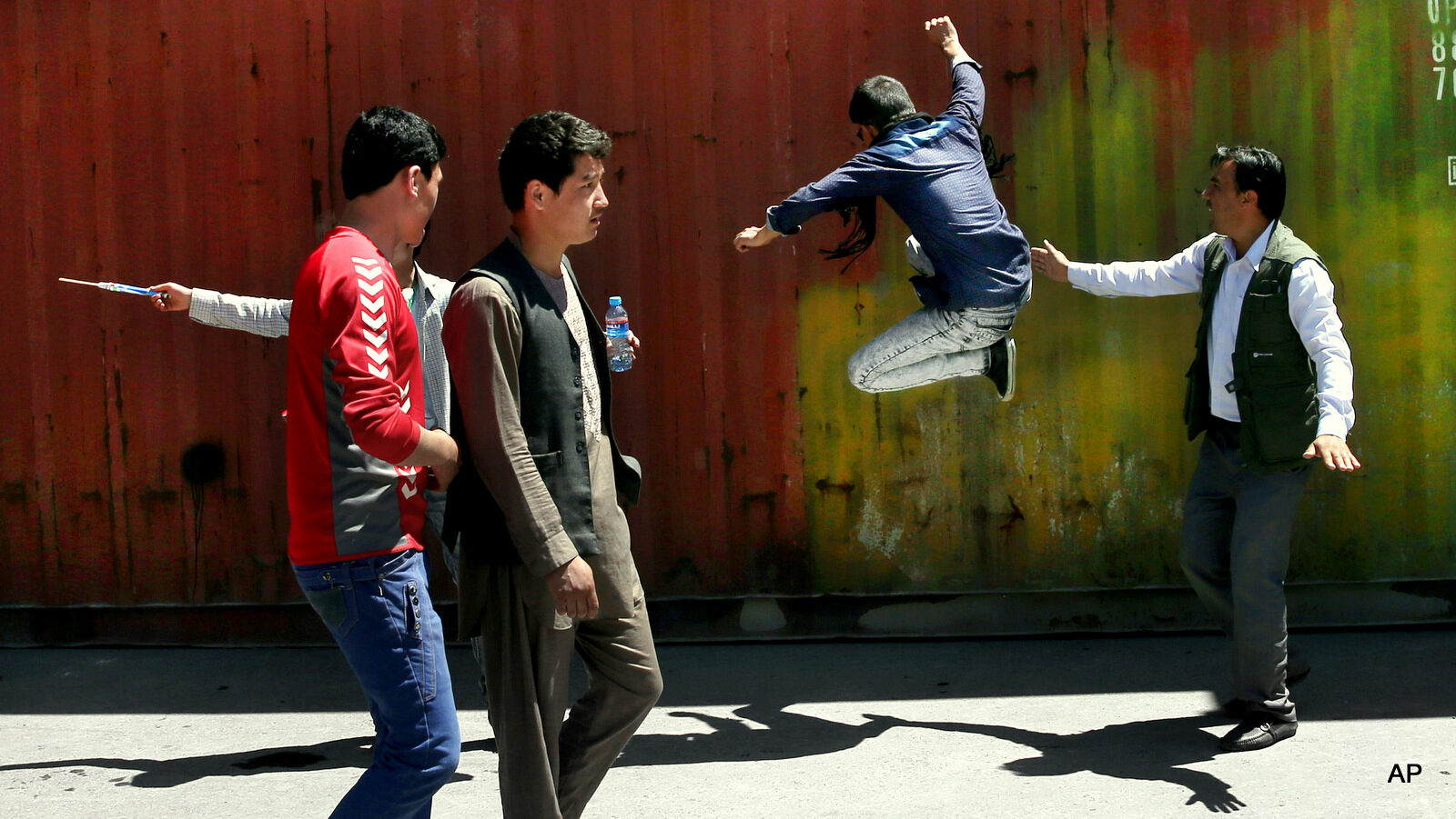 A protester, second right, kicks a container during a massive anti-government protest in Kabul, Afghanistan, Monday, May 16, 2016. Authorities locked down Afghanistan's capital Monday as tens of thousands of members of an ethnic minority group marched through the streets to protest the proposed route of a power line.