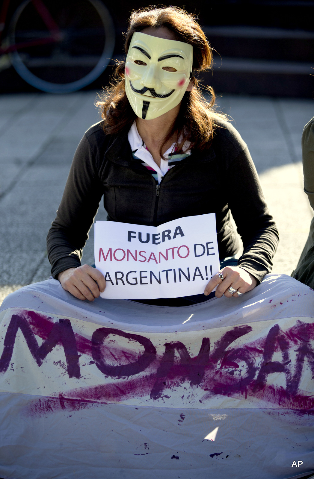 A demonstrator wearing as Guy Fawkes mask holds a sign that reads in Spanish "Get out Monsanto from Argentina" near the offices of the U.S.-based company Monsanto in Buenos Aires, Argentina, Saturday, May 25, 2013. 