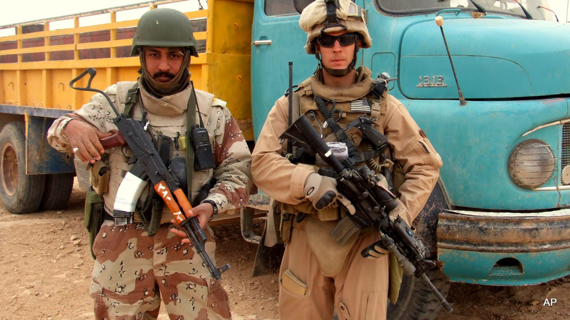 HOLD FOR USE WITH STORY MOVING FRIDAY, MAY 20, 2016-This 2007 photo provided by Chase Millsap shows Millsap with the Captain standing next to a suspected truck bomb following a successful raid in Al Anbar, Iraq. After three tours of duty in warn-torn Iraq, including one that nearly took his life, Millsap returned to the United States to earn a master's degree in public policy and get on with a civilian life. For the past two years, the former Green Beret soldier has been fighting another battle to gain political asylum for his brother in arms, a man he simply calls The Captain, a soldier who fought alongside him during two of Millsap's tours in Iraq. (Chase Millsap via AP)