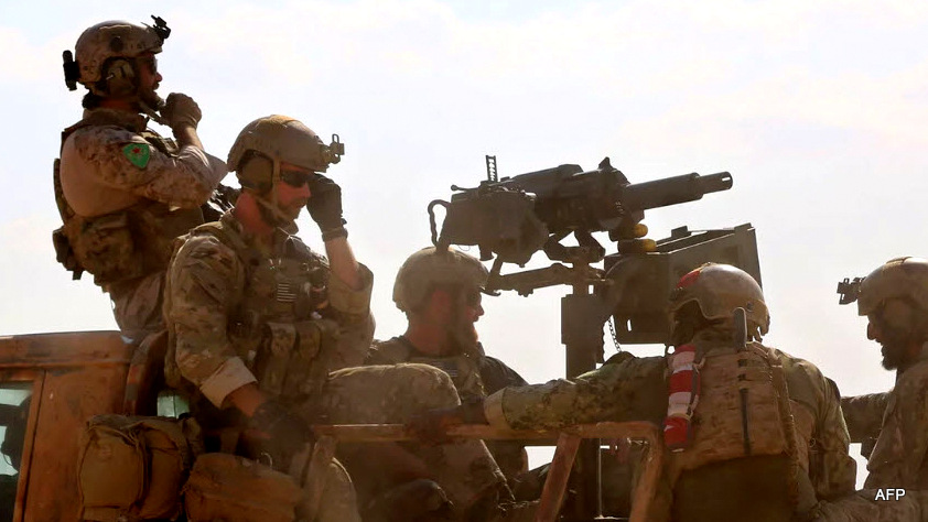 Armed men in uniform identified by Syrian Democratic forces as US special operations forces ride in the back of a pickup truck in the village of Fatisah in the northern Syrian province of Raqa, May 25, 2016.