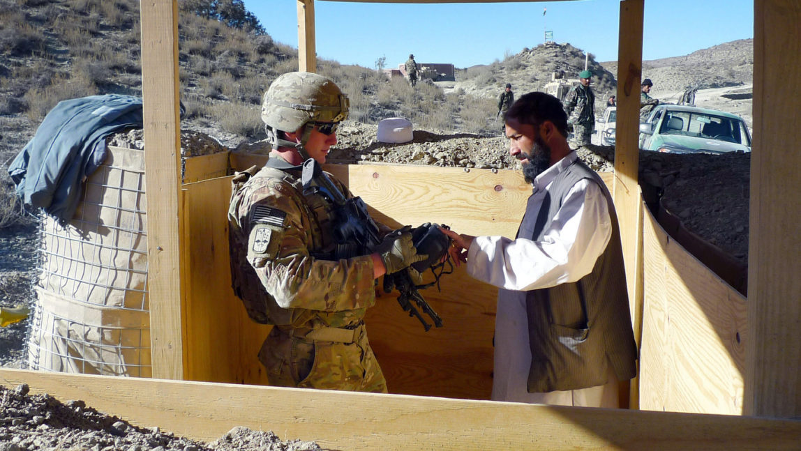 In this Thursday, Dec. 1, 2011 photo, a U.S. soldier, left, with Apache Company of Task Force 3-66 Armor, out of Grafenwoehr, Germany, fingerprints a man passing through a police checkpoint at Gulruddin pass in Sar Hawza district of Paktika province, south of Kabul, Afghanistan. (AP Photo/Heidi Vogt)