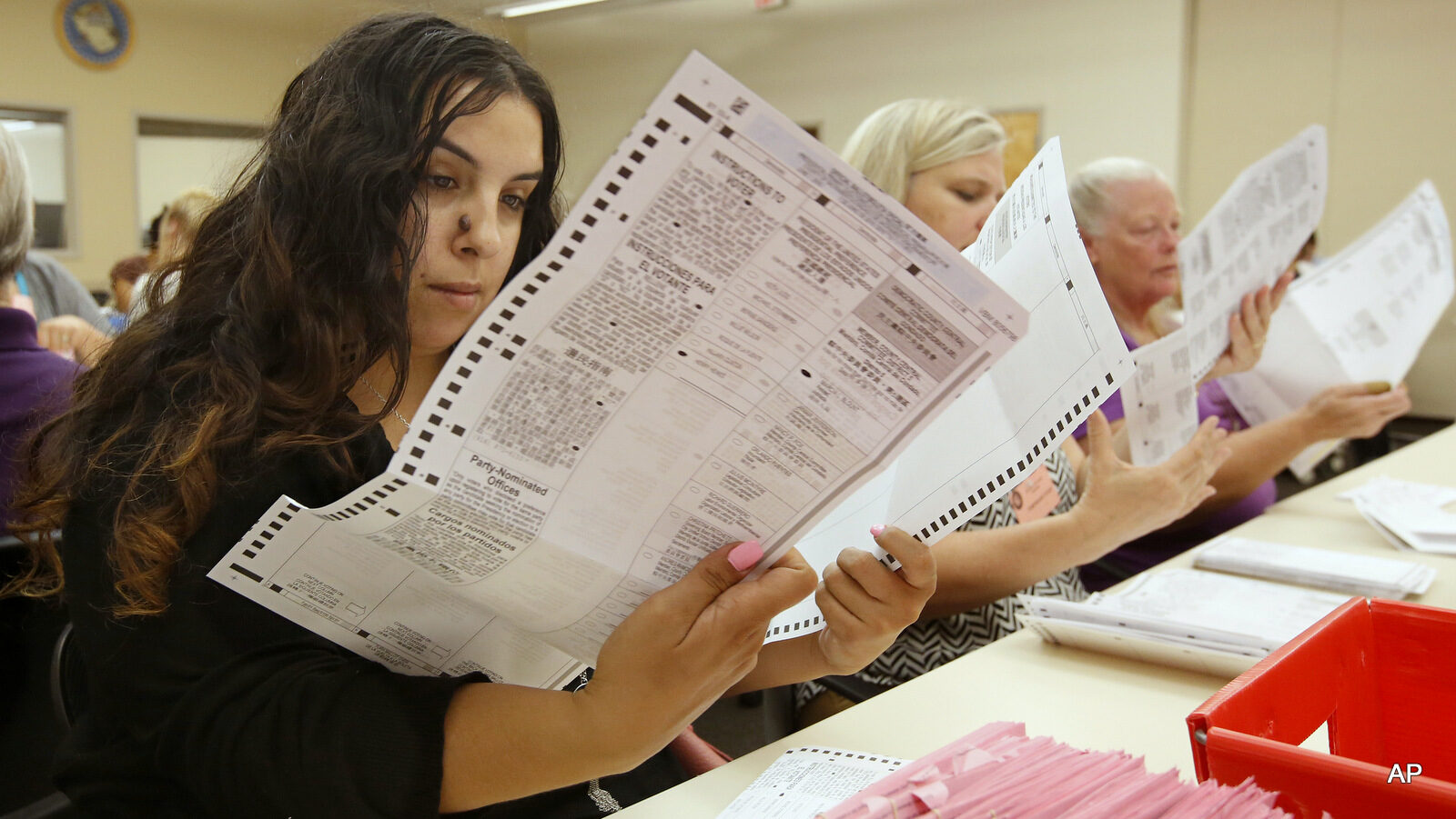Sabrina Riddle, left, a temporary worker at the Sacramento County Registrar of Voters office, inspects a mail-in ballot Monday, June 6, 2016, in Sacramento, Calif. Voter turnout is expected to be higher then normal in the nation's most populous state for Tuesday's primary.