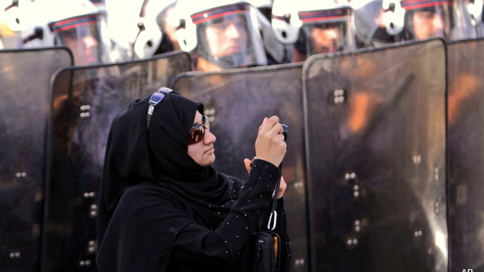 An anti-government protester stands in front of riot police while photographing other demonstrators in Manama, Bahrain. On Tuesday, June, 14, 2016, Bahrain said it has suspended all activities by Al-Wefaq, the largest Shiite opposition political group, and frozen its assets amid a widening crackdown on dissent, five years after the country’s Arab Spring protests.