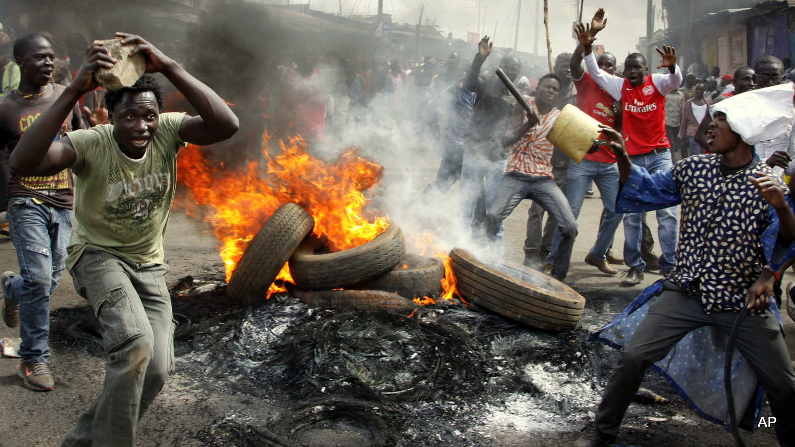 Opposition supporters stand by burning barricades set up in protest over a pro-government MP whom they allege made offensive remarks about the opposition leader, in the Kibera slum of Nairobi, Kenya Tuesday, June 14, 2016. The protesters then threw rocks and engaged in running battles with police who fired teargas and chased them through the streets and alleys. (AP Photo/Khalil Senosi)