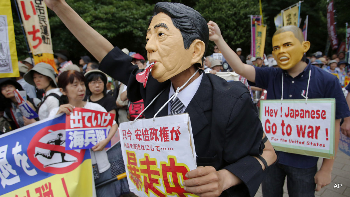 Protesters wearing masks of Japanese Prime Minister Shinzo Abe, center, and U.S. President Barack Obama, right, attend a rally in front of the National Diet building in Tokyo Sunday, June 19, 2016. Tens of thousands of Japanese on Sunday protested the presence of U.S. military bases on the southwestern island of Okinawa, many of them wearing black to mourn the rape and killing of a local woman in which a former U.S. Marine is a suspect. The placard, center, reads: "Currently, the Abe administration is going out of control accompanying all Japanese people." (AP Photo/Shizuo Kambayashi)