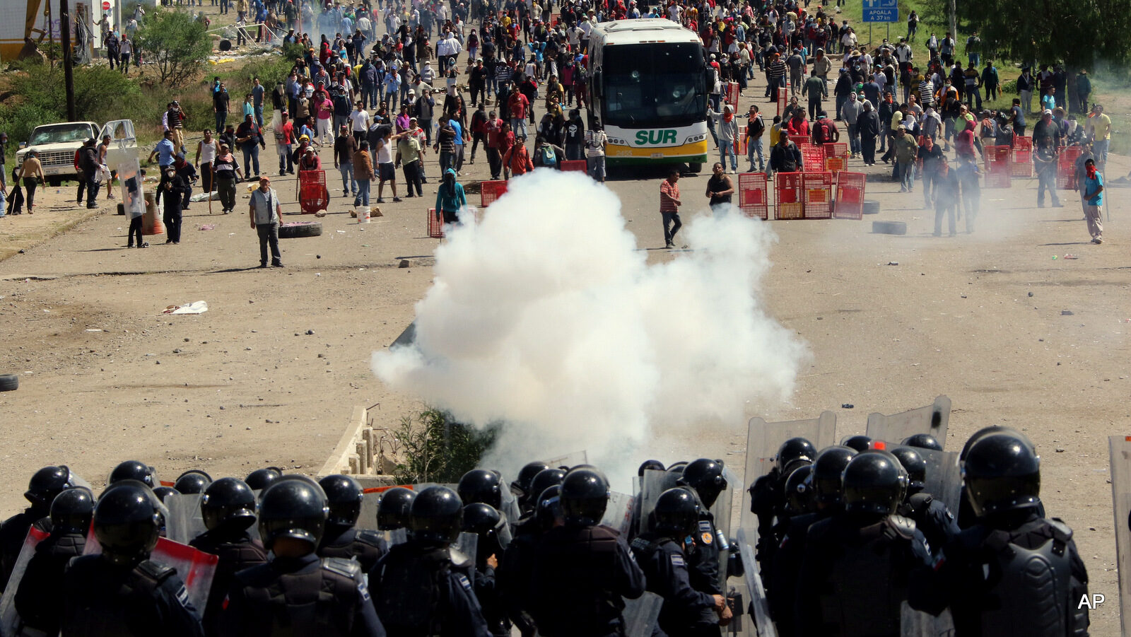 Riot police battle with protesting teachers who were blocking a federal highway in the state of Oaxaca, near the town of Nochixtlan, Mexico, Sunday, June 19, 2016. The teachers are protesting against plans to overhaul the country's education system which include federally mandated teacher evaluations.