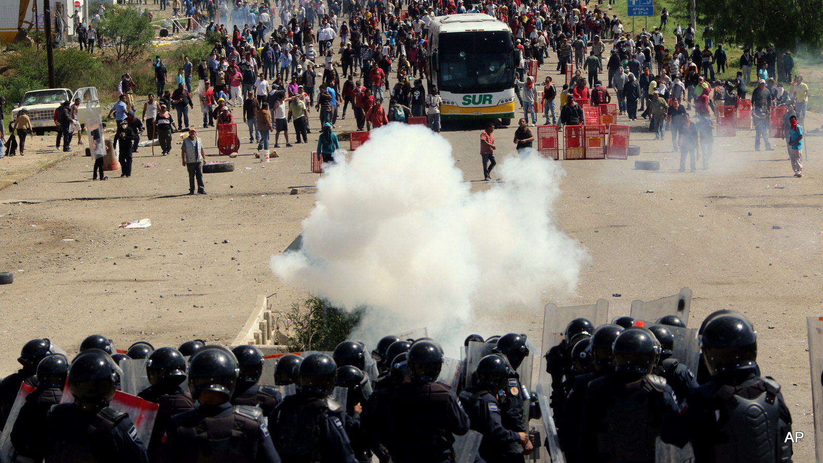 Riot police battle with protesting teachers who were blocking a federal highway in the state of Oaxaca, near the town of Nochixtlan, Mexico, Sunday, June 19, 2016. The teachers are protesting against plans to overhaul the country's education system which include federally mandated teacher evaluations.