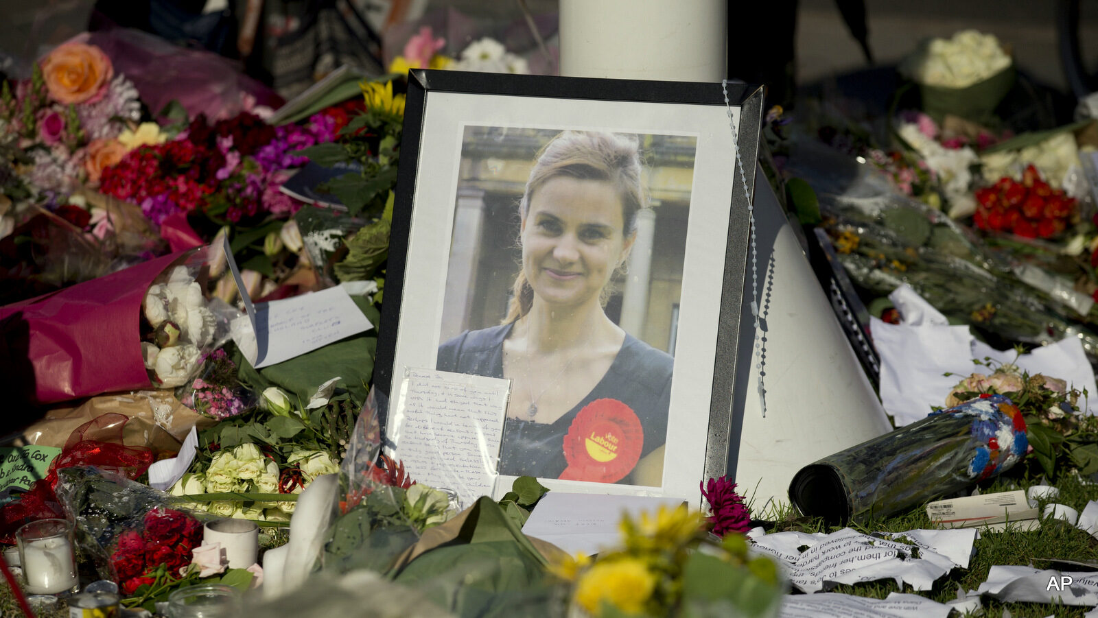 A photograph of Jo Cox, the 41-year-old Member of Parliament fatally shot last week in northern England, stands amongst tributes laid in her memory in Parliament Square, London, after a service of prayer and remembrance to commemorate her, Monday, June 20, 2016. The mother of two was shot on Thursday afternoon in her constituency near Leeds. The man charged with her slaying made a brief appearance in court by video link from prison Monday. (AP Photo/Matt Dunham)