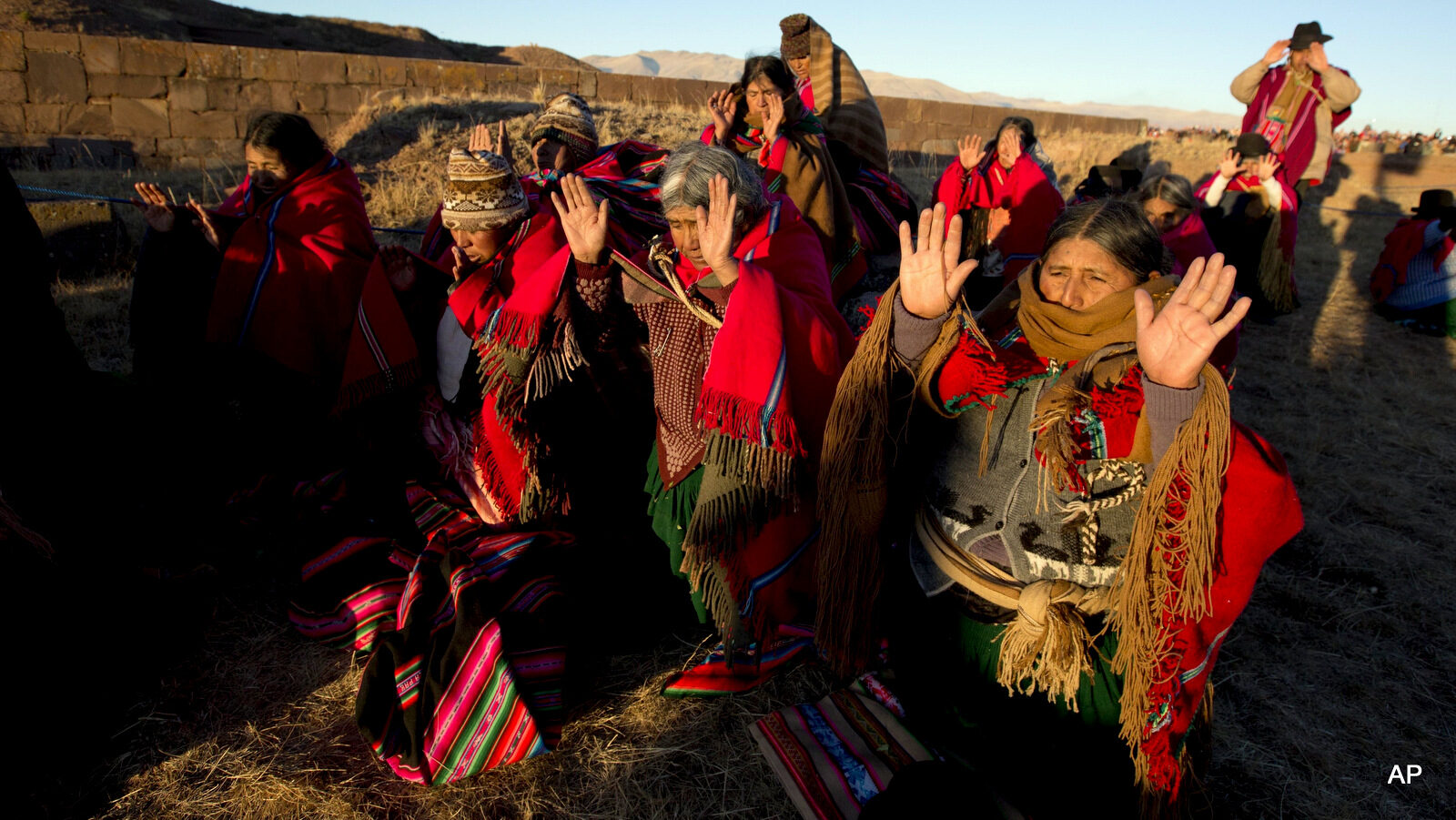 Aymara indigenous hold up their hands to receive the first rays of sunlight in a New Year's ritual in the ruins of the ancient city Tiwanaku, Bolivia, early Tuesday, June 21, 2016. Bolivia's Aymara Indians are celebrating the year 5,524 as well as the Southern Hemisphere's winter solstice, which marks the start of a new agricultural cycle.