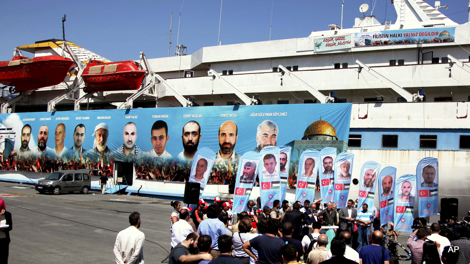 Turks gather in Istanbul, on the fourth anniversary of the Mavi Marmara ship, background, the lead boat of a flotilla headed to the Gaza Strip which was stormed by Israeli naval commandos in a predawn raid killing at least 9 passengers and wounding dozens more. Turkey's Prime Minister Binali Yildirim announced Monday, June 27, 2016, that Turkey and Israel have reached a deal to normalize ties after six years of strain.