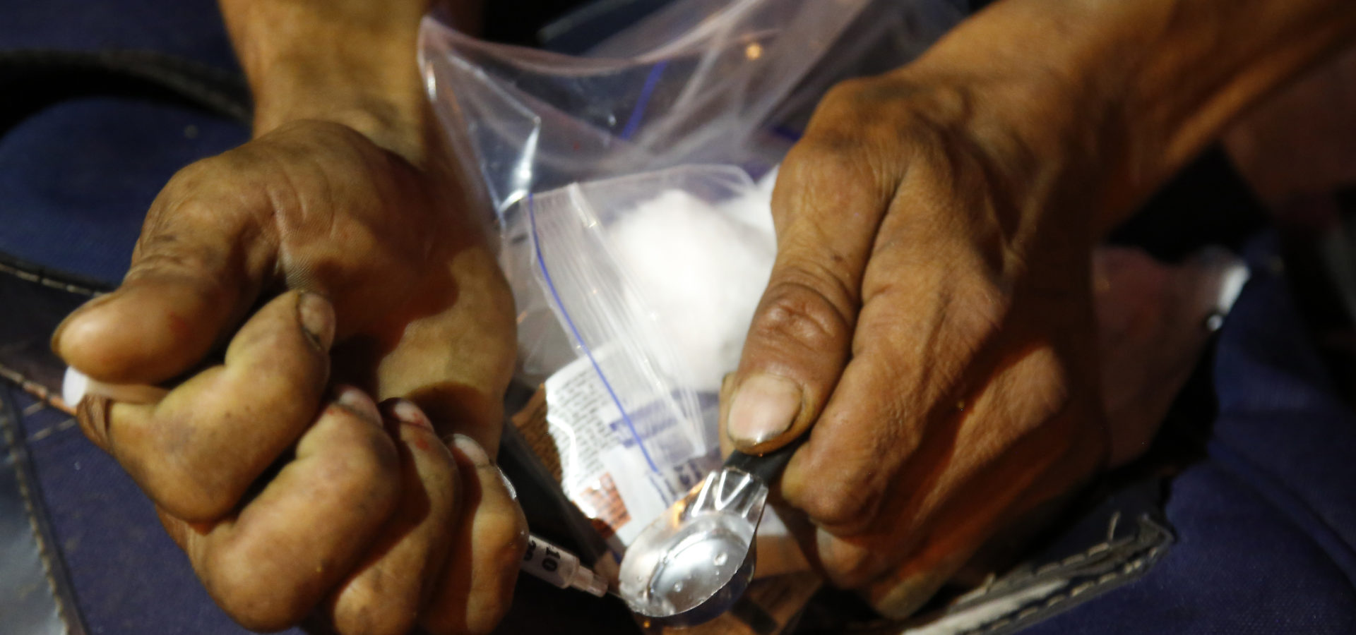 An addict prepares shoot up heroin after receiving a kit including a spoon, a rubber tube, cotton, sterilized water and clean syringes distributed by a program sponsored by the Open Society Foundation and government agencies in Dosquebradas, Colombia. (AP/Fernando Vergara)